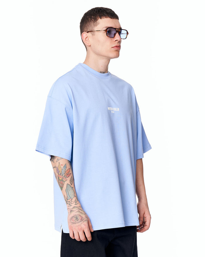 Martin Valen "Slogan" oversized blue men's T‑shirt three‑quarter view, dropped shoulder and subtle chest logo