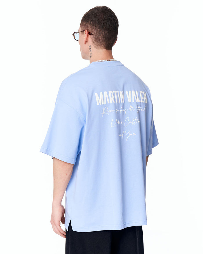 Martin Valen blue "Slogan" oversized men's T‑shirt rear view on model, large white Martin Valen print across upper back and relaxed fit